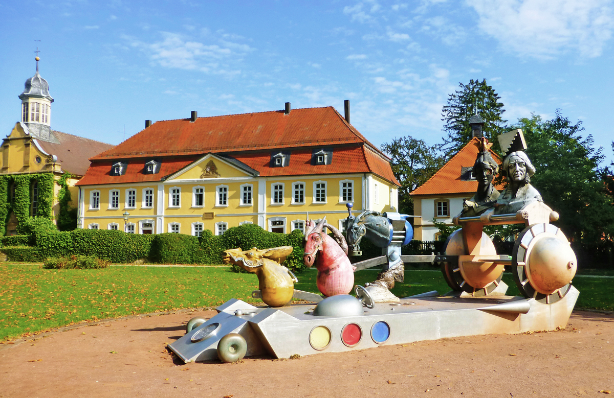 Im Vordergrund die Großplastik Chariot 1889 (Wagenlenker), im Hintergrund links die ehemalige Schlosskapelle, heute das Atelier von Jürgen Goertz, und daneben das Rentamt in Eichtersheim.
